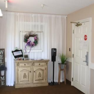A cozy entrance area with a wooden cabinet, welcome sign, floral decor, and a door.