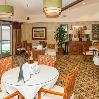 A well-appointed dining room featuring elegantly set tables, comfortable chairs, and warm lighting.