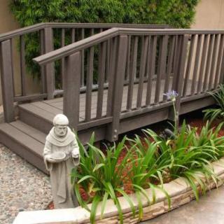 A small garden bridge with a statue surrounded by greenery.