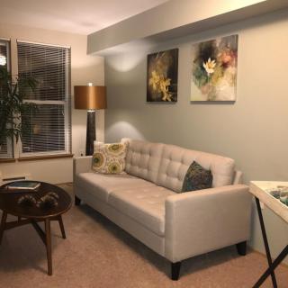 A cozy living room with a comfortable sofa, artwork on the wall, and soft lighting.