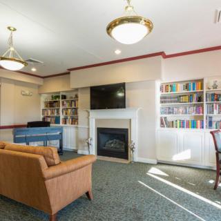 A cozy living room with a fireplace, bookshelves, and a sofa under elegant lighting.