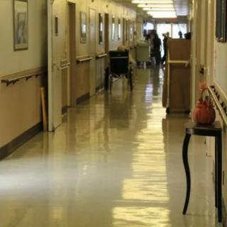 A quiet hospital hallway with a wheelchair at the far end.