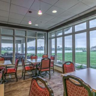 A dining area with tables and chairs, featuring large windows offering a scenic view.