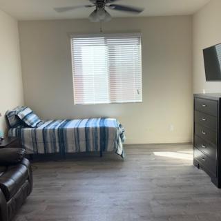 A simple bedroom with a single bed, striped bedding, and a wall-mounted television beside a dresser.