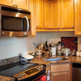 A modern kitchen with wooden cabinets and granite countertops, featuring a microwave and stove.