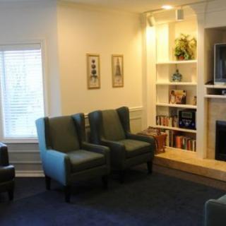 A cozy living room with comfortable chairs, a bookshelf, and warm lighting.