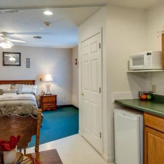 A cozy room with a bed, table, and kitchenette area.