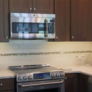 A modern kitchen setup featuring a stove and microwave with wooden cabinets and a sleek countertop.