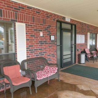 A cozy front porch with chairs and an entrance to a brick building.