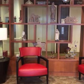 A stylish waiting area featuring red chairs and a decorative shelving unit.