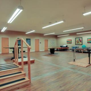 An empty rehabilitation center with exercise equipment, stairs, and handrails.