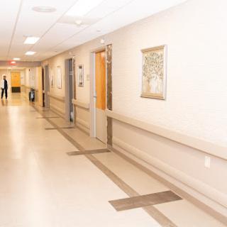 A well-lit hospital corridor with doors and art on the walls.