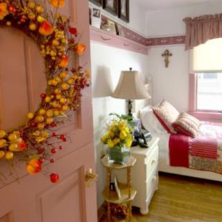 A cozy bedroom adorned with fall-themed decorations, including a wreath on the door and colorful accents throughout the room.