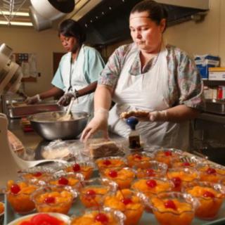 Two chefs preparing desserts in a kitchen.