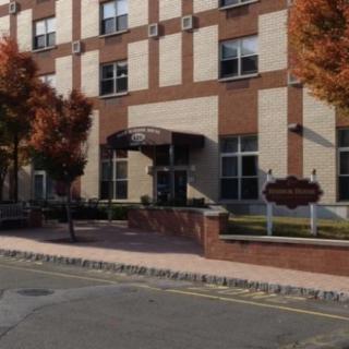 The entrance of a brick building with autumn trees lining the sidewalk.