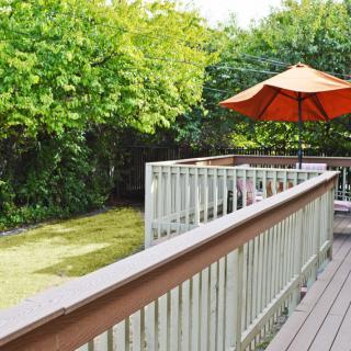A tranquil outdoor deck area featuring a patio umbrella, surrounded by lush greenery.