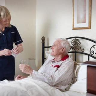 A nurse assisting an elderly man in a bedroom, providing care and support.