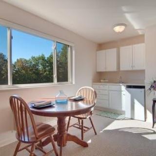 A cozy kitchen and dining area with a table set by the window, letting in ample sunlight.