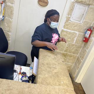 A receptionist assisting at the front desk while wearing a mask.