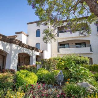 A sunny day view of a residential building with lush gardens and balconies.