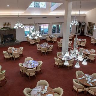 An empty dining room with elegantly set tables and chandeliers, creating a cozy atmosphere.