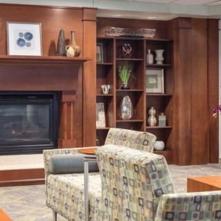 A cozy living room with a fireplace flanked by wooden shelves filled with decorative items, and comfortable armchairs in front of it.
