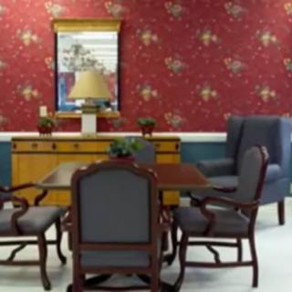 A traditional dining room setup with a wooden table, chairs, and a mirror on a wallpapered wall.