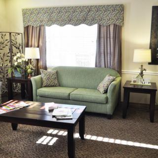 A cozy living room featuring a green sofa, coffee table, and elegant curtains.