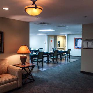 A cozy interior space featuring a seating area with a sofa and lamp, leading into a dining area.