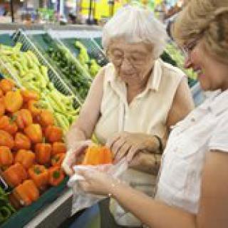 Two women selecting bell peppers at a grocery store.
