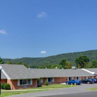A view of a motel surrounded by mountains with cars parked in front.