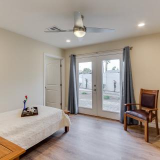 A minimalist bedroom with a comfortable bed, wooden chair, and French doors leading outside.