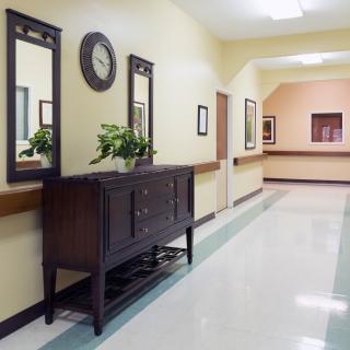 A well-decorated hallway with mirrors, a clock, and a wooden cabinet.