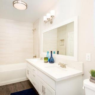 A stylish and modern bathroom featuring a sleek vanity, large mirror, and elegant lighting.