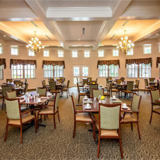 A spacious dining room featuring elegant tables and chairs, illuminated by beautiful chandeliers.