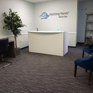 A modern reception area featuring a clean design with blue chairs, a potted plant, and a white front desk.