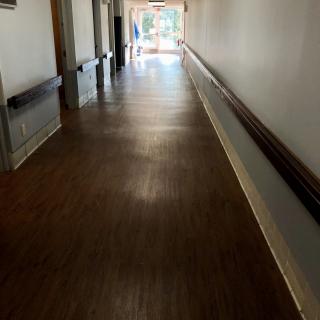 An empty hallway with wooden flooring and handrails on the walls.