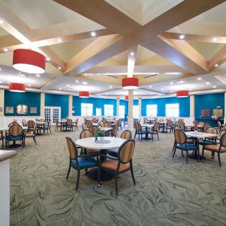 A spacious dining area with modern decor, featuring tables, chairs, and stylish lighting fixtures.