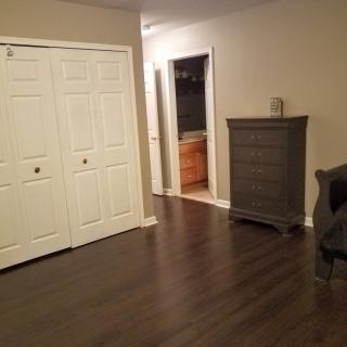 A clean, empty room with wood flooring and a dresser beside a closet.
