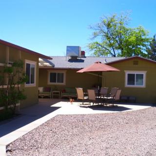 A cozy house with a gravel patio featuring outdoor furniture and an umbrella on a sunny day.
