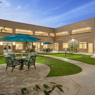 A serene courtyard with outdoor furniture and umbrellas in front of a modern building.