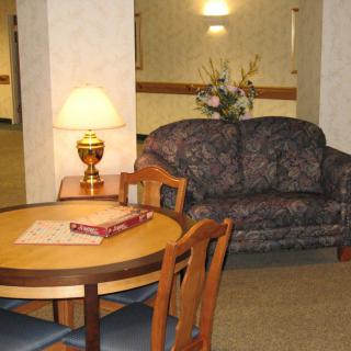 A cozy living room area featuring a round table with chairs, a couch, and a lamp.
