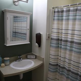 A cozy and neatly arranged bathroom featuring a sink, mirror, and a striped shower curtain.