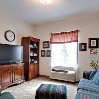 A cozy living room with a television, bookshelf, and comfortable seating.
