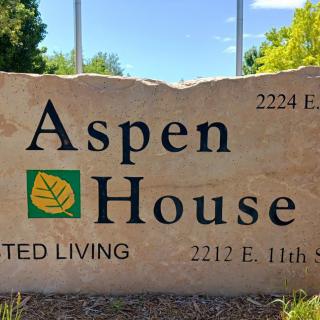 A stone sign for Aspen House Assisted Living with an address displayed.
