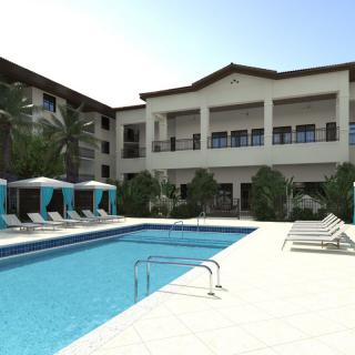 A luxury resort with a large swimming pool and stylish outdoor amenities under a clear blue sky.