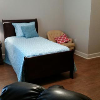 A cozy bedroom with a single bed adorned with blue bedding, accompanied by a chair in the corner.
