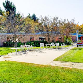 A serene outdoor area featuring green lawns, trees, and a poolside relaxation zone.