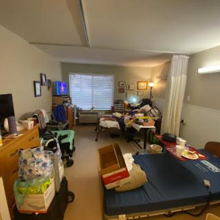 A cluttered room featuring a bed, television, and various personal items.
