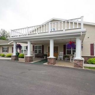A front view of a building entrance with columns, a porch, and decorative hanging plants.